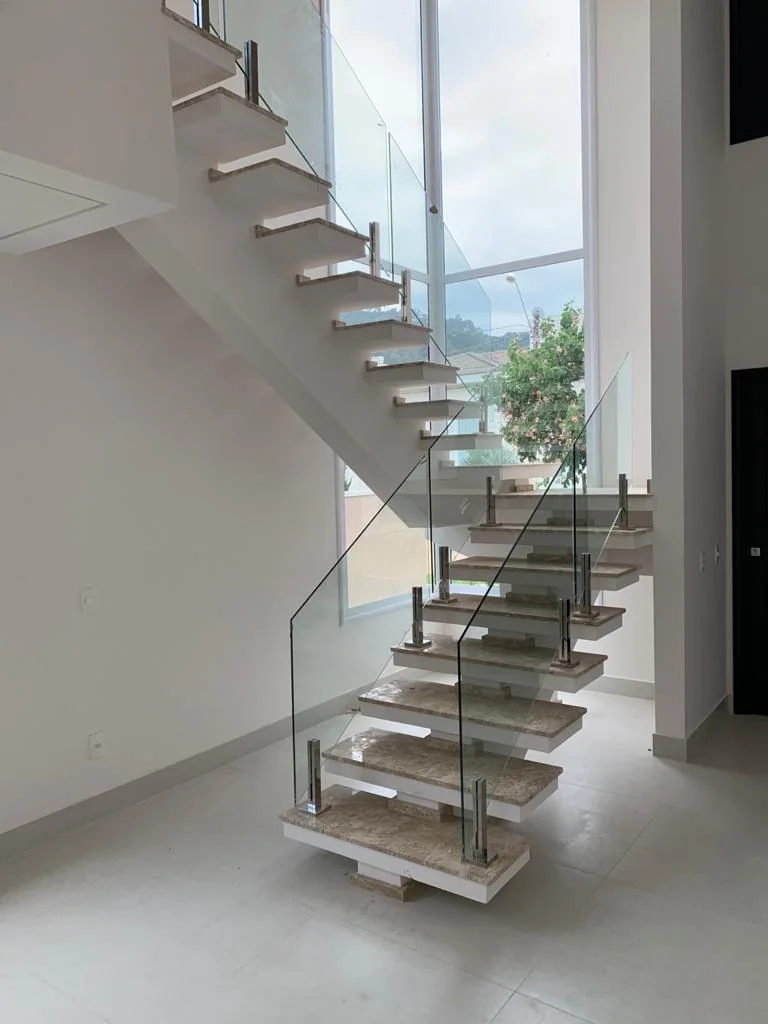 Escada branca com guarda-corpo de vidro e acabamento moderno